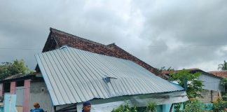 Warga Desa Tampo, Kecamatan Cluring, Banyuwangimembersihkan atap rumah yang jebol akibat terjangan puting beliung, Kamis (15/9/2022) siang.