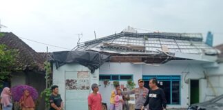 Warga membersihkan atap rumah yang rusak diterjang angin putting beliung, Kamis (29/12/2022) siang.