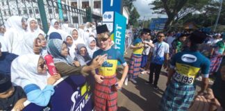 Pembalap asing TdBI 2024 menggunakan sarung dan songkok berfoto bersama warga di start etape pertama, Senin (22/7/2024). (Foto/udi)