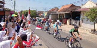 Para pelajar di Desa Kemiren, Banyuwangi menyambut para pembalap etape 4 TdBI, Kamis (25/7/2024). (Foto/udi)