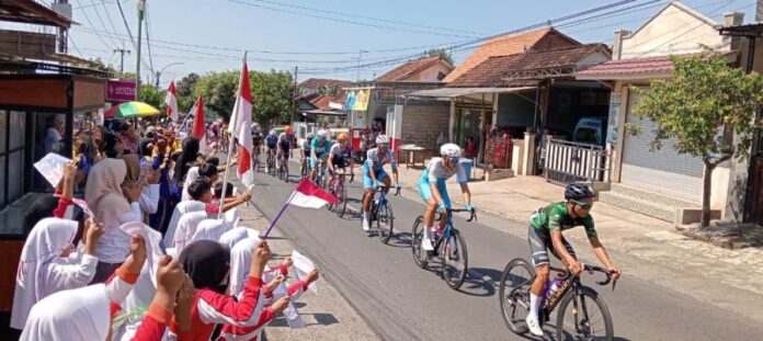 WhatsApp Image 2024-07-25 at 13.12.30 Para pelajar di Desa Kemiren, Banyuwangi menyambut para pembalap etape 4 TdBI, Kamis (25/7/2024). (Foto/udi)