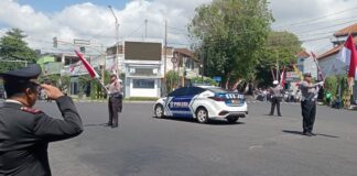 Personel Satlantas Polresta Banyuwangi mengajak pengguna jalan hening dan hormat bendera Merah Putih di momen detik-detik Proklamasi HUT Kemerdekaan RI, Sabtu (17/8/2024). (Foto/udi)