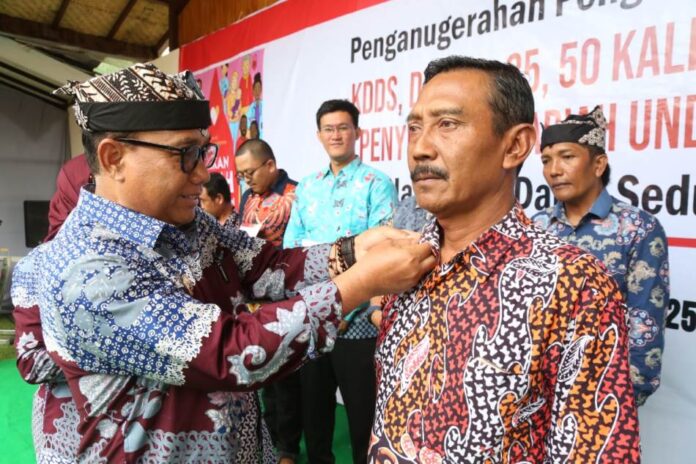 Wabup Banyuwangi Mujiono menyerahkan lencana kepada pendonor suka rela di PMI Banyuwangi. (Foto/Humas pemkab)