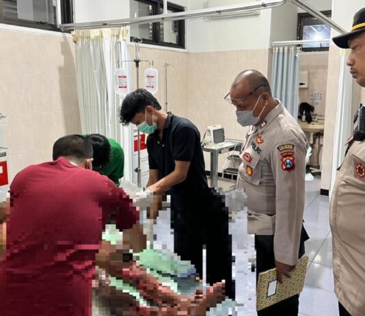 Personel Polsek Gambiran, Banyuwangi mendampingi pasutri yang terbakar di RSUD Genteng, Jumat (24/4/2026) malam. (Foto/ist)