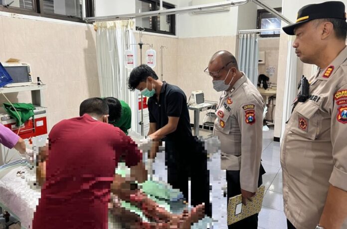 Personel Polsek Gambiran, Banyuwangi mendampingi pasutri yang terbakar di RSUD Genteng, Jumat (24/4/2026) malam. (Foto/ist)